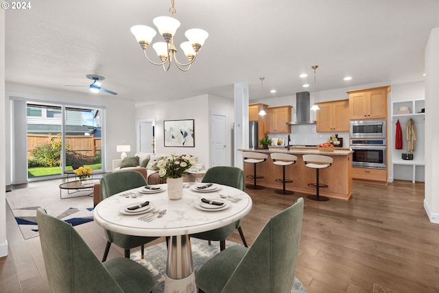 dining room featuring ceiling fan with notable chandelier and dark hardwood / wood-style flooring