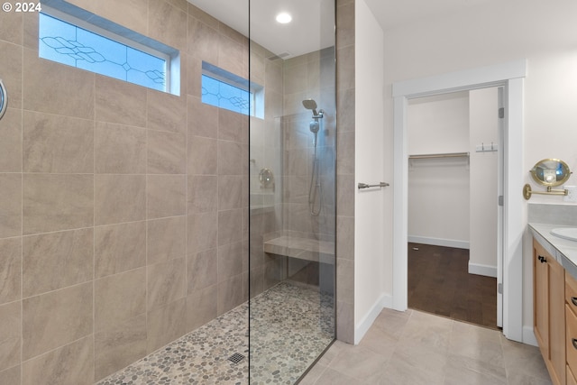 bathroom featuring a tile shower, vanity, and tile patterned flooring