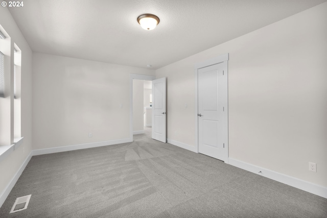 spare room featuring light colored carpet and a textured ceiling