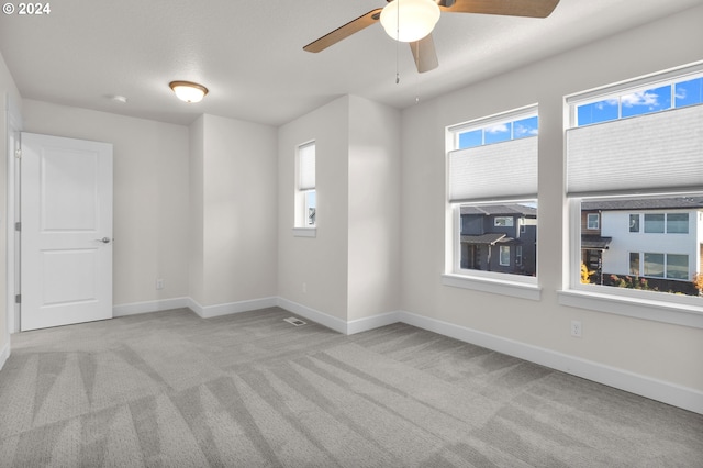 carpeted empty room featuring ceiling fan and a wealth of natural light