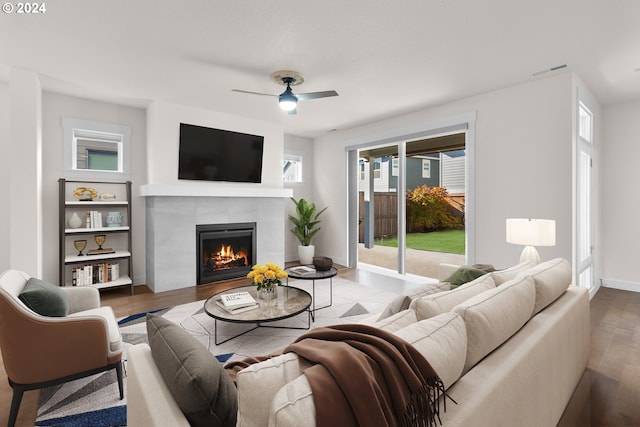 living room with a tiled fireplace, ceiling fan, and wood-type flooring