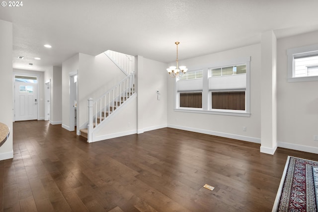 unfurnished dining area featuring a notable chandelier, dark wood-type flooring, and a textured ceiling