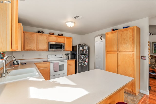 kitchen featuring visible vents, light countertops, appliances with stainless steel finishes, a sink, and a peninsula