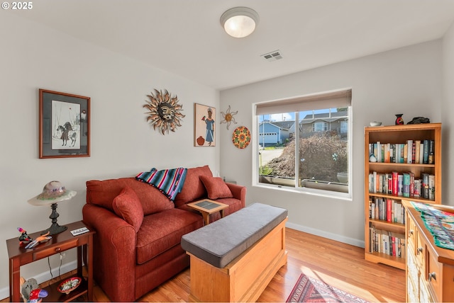 living room featuring baseboards, visible vents, and light wood finished floors