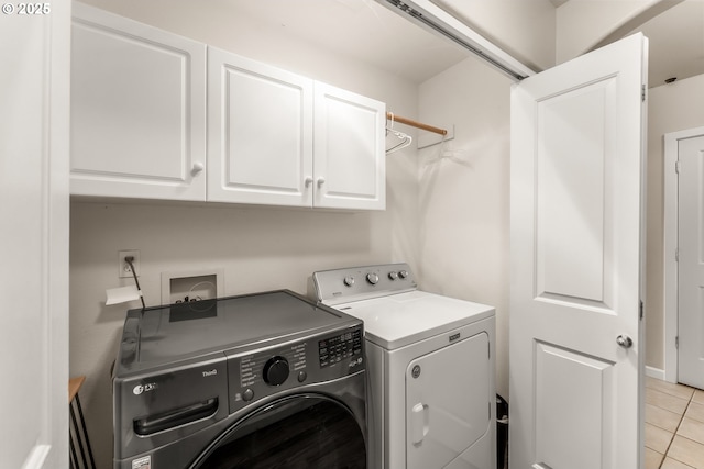 washroom featuring light tile patterned floors, separate washer and dryer, and cabinet space