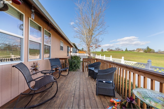 wooden terrace with a rural view, a yard, and fence