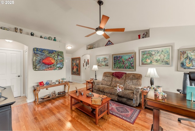 living area with light wood-style flooring, vaulted ceiling, arched walkways, and ceiling fan