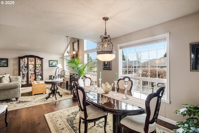 dining room featuring a textured ceiling, hardwood / wood-style flooring, and baseboards