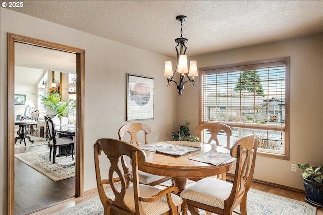 dining space with a textured ceiling, light wood finished floors, and a chandelier