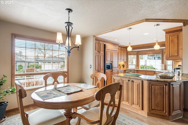 dining room with a textured ceiling, light wood-style flooring, and an inviting chandelier