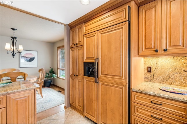 kitchen with decorative backsplash, light stone counters, hanging light fixtures, an inviting chandelier, and light tile patterned flooring