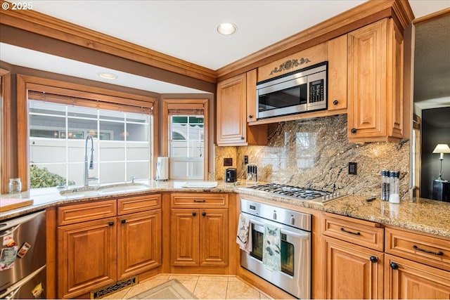 kitchen with visible vents, light stone counters, a sink, stainless steel appliances, and backsplash