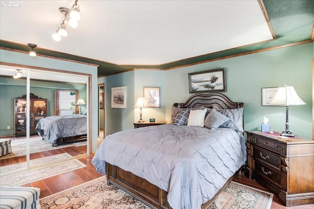 bedroom featuring a closet, ornamental molding, and wood finished floors