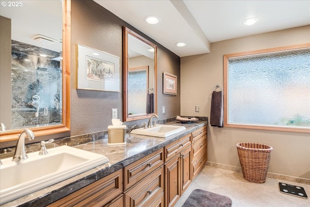 bathroom with baseboards, a sink, a marble finish shower, and double vanity