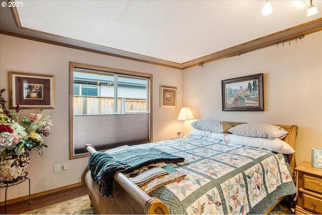 bedroom featuring ornamental molding, baseboards, and wood finished floors