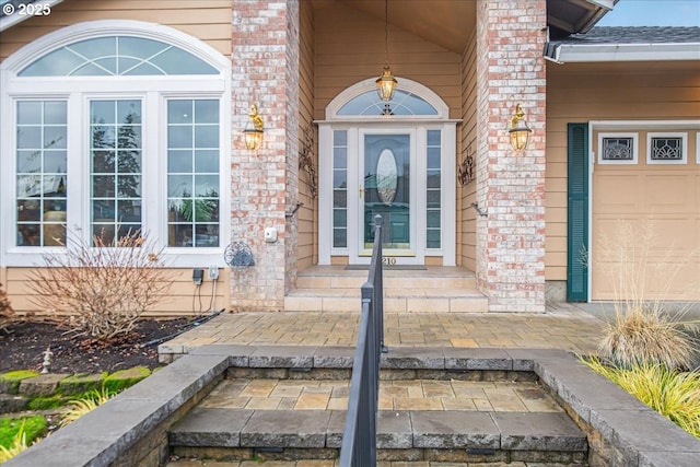 property entrance with an attached garage and brick siding