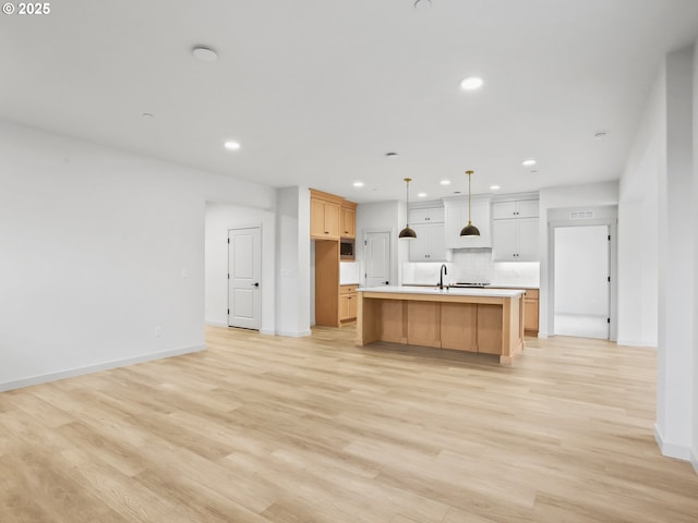 kitchen with light wood-style flooring, a kitchen island with sink, light countertops, premium range hood, and recessed lighting