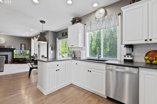 8775 SW Comanche Way, Tualatin, OR 97062 - kitchen featuring dishwasher, dark countertops, a tiled fireplace, open floor plan, and tasteful backsplash