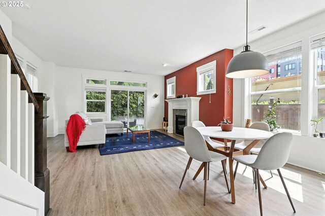 18 NE Cook St, Portland, OR 97212 - dining space featuring wood finished floors, a fireplace with flush hearth, and plenty of natural light