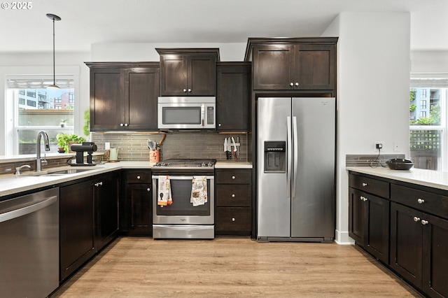 18 NE Cook St, Portland, OR 97212 - kitchen featuring stainless steel appliances, light countertops, light wood-style floors, decorative backsplash, and pendant lighting