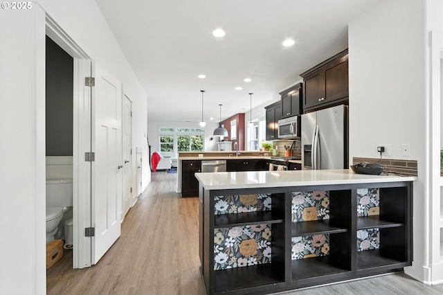 18 NE Cook St, Portland, OR 97212 - kitchen featuring stainless steel appliances, a peninsula, light wood-style flooring, light countertops, and recessed lighting