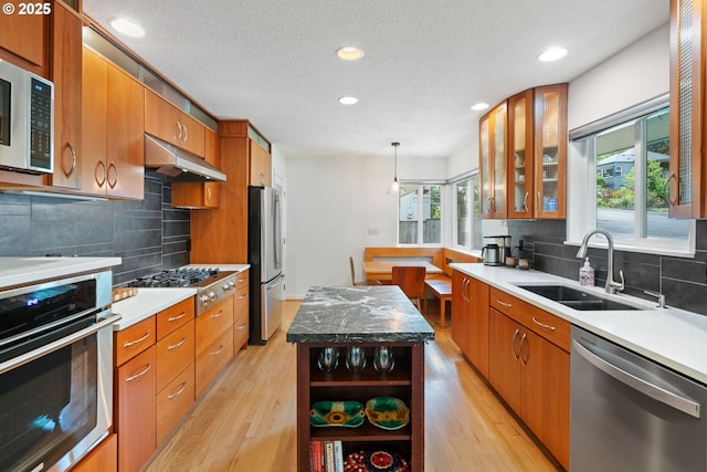 9004 SW 36th Ave, Portland, OR 97219 - kitchen with appliances with stainless steel finishes, a sink, light wood-style floors, brown cabinetry, and recessed lighting