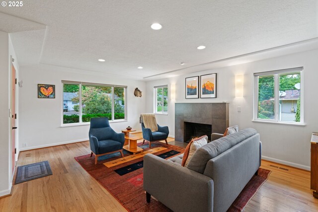 9004 SW 36th Ave, Portland, OR 97219 - living room featuring a tile fireplace, baseboards, light wood-style floors, a textured ceiling, and recessed lighting
