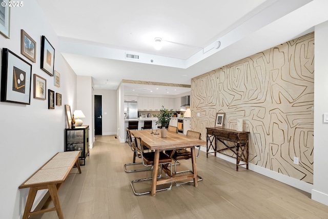 dining space featuring visible vents, light wood-style flooring, and baseboards