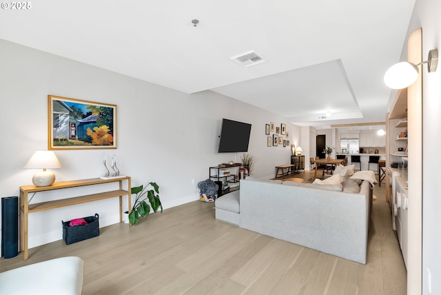 living room featuring light wood-type flooring, visible vents, and baseboards