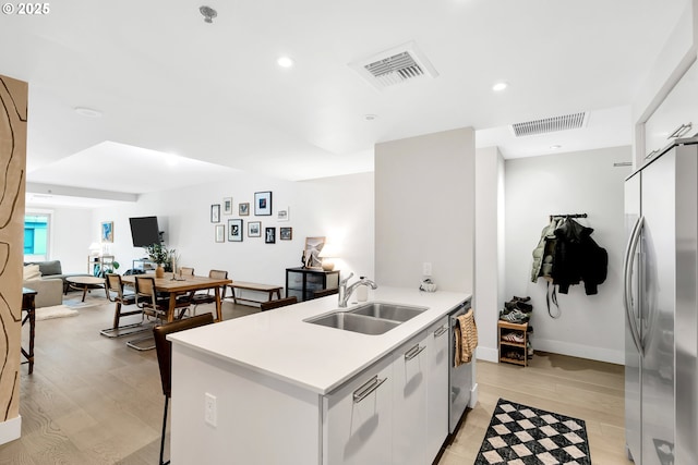 kitchen featuring appliances with stainless steel finishes, light wood-type flooring, visible vents, and a sink