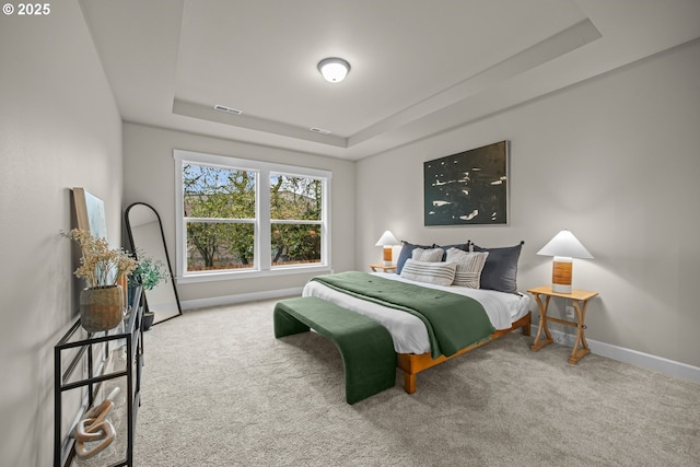 carpeted bedroom featuring a tray ceiling, baseboards, and visible vents