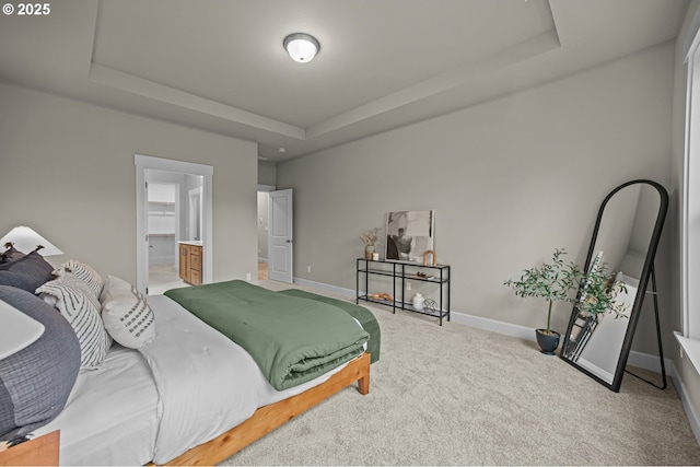 carpeted bedroom with a tray ceiling and baseboards