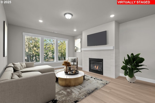 living room featuring a tile fireplace and light wood-type flooring