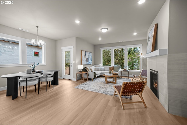 living area with a notable chandelier, recessed lighting, light wood-style flooring, and a tile fireplace