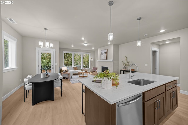 kitchen with visible vents, a fireplace, a sink, stainless steel dishwasher, and light wood-type flooring