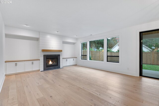 unfurnished living room featuring light wood-type flooring, a fireplace, and baseboards