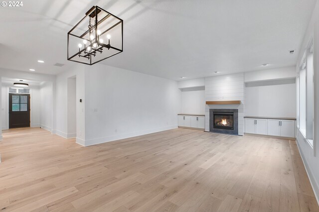 unfurnished living room with light wood finished floors, a fireplace, recessed lighting, and baseboards