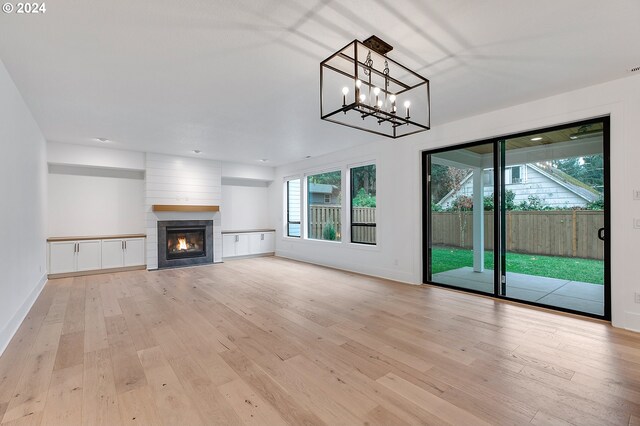 unfurnished living room featuring a wealth of natural light, a large fireplace, baseboards, and light wood finished floors