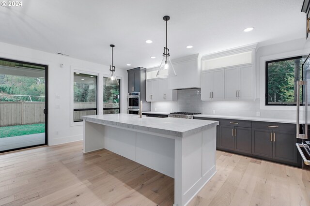 kitchen with light countertops, a healthy amount of sunlight, backsplash, and light wood-style floors