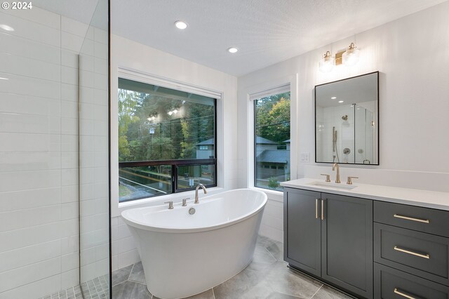 full bath featuring recessed lighting, a soaking tub, a stall shower, vanity, and a textured ceiling