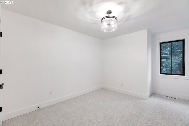 unfurnished room featuring baseboards, visible vents, and light colored carpet