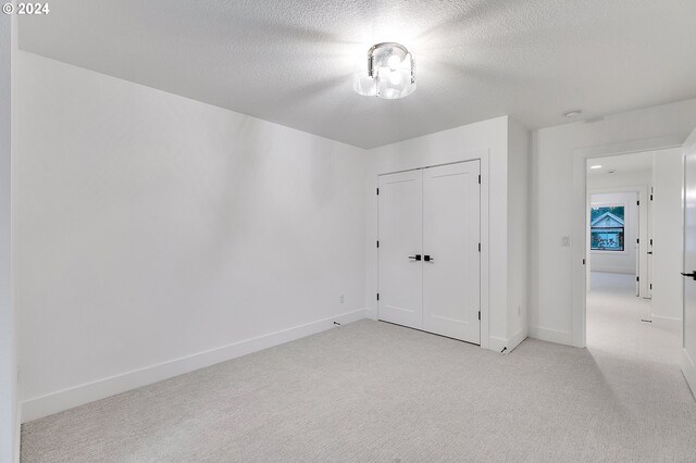 unfurnished room with light carpet, a textured ceiling, and baseboards