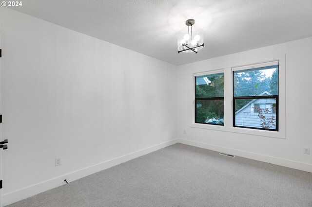 unfurnished room featuring an inviting chandelier, baseboards, visible vents, and light colored carpet