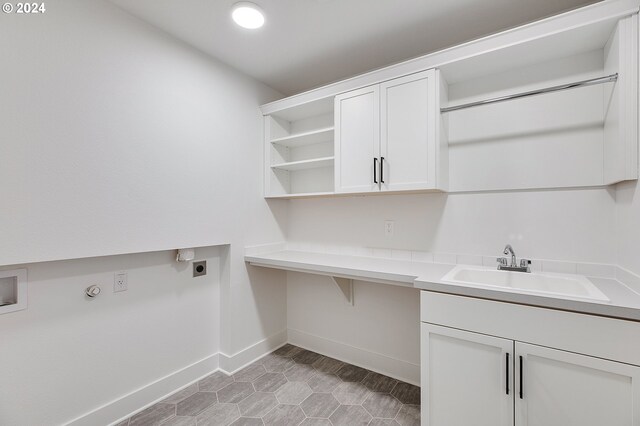 laundry room featuring a sink, cabinet space, baseboards, and hookup for an electric dryer