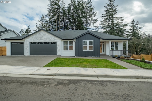 view of front facade with a garage, concrete driveway, fence, board and batten siding, and a front yard