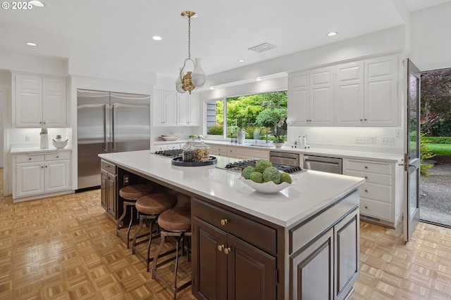1890 S Greenwood Rd, Portland, OR 97219 - kitchen with appliances with stainless steel finishes, light countertops, a center island, white cabinetry, and recessed lighting