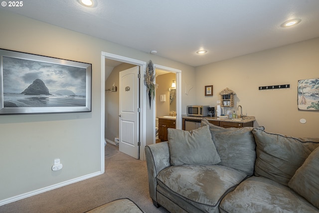 carpeted living room featuring baseboards, a sink, and recessed lighting