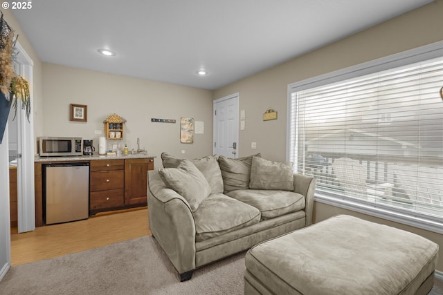 living area featuring light wood-type flooring, bar, recessed lighting, and light colored carpet