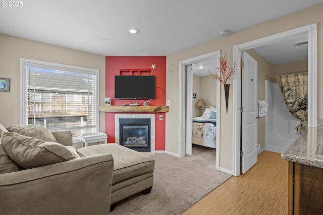 living room with a tiled fireplace, light colored carpet, baseboards, visible vents, and recessed lighting