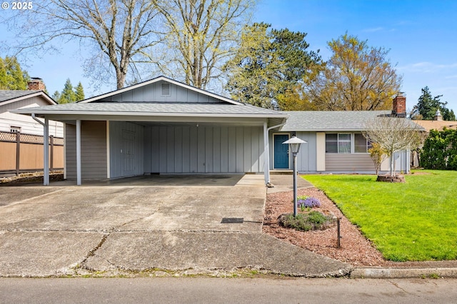 ranch-style house featuring a shingled roof, a front lawn, driveway, and a carport